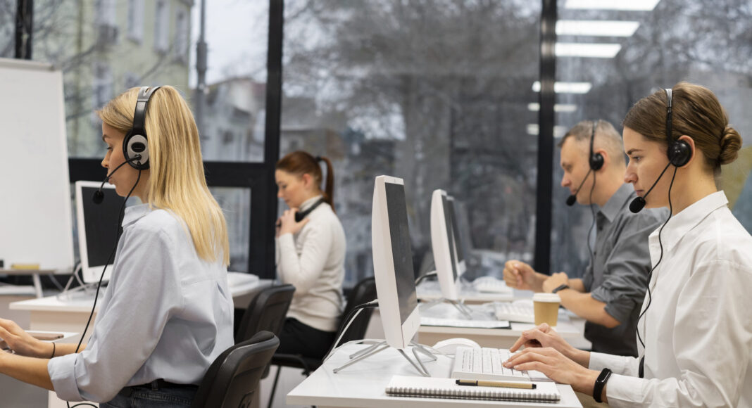 Il personale di un call center lavora al computer e parla tramite cuffie, gestendo le chiamate di telemarketing con professionalità ed efficienza.