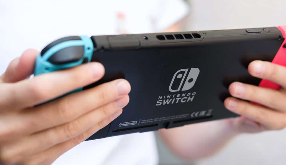 Persona che tiene in mano un Nintendo Switch 2 con i controller Joy-Con blu e rosso.