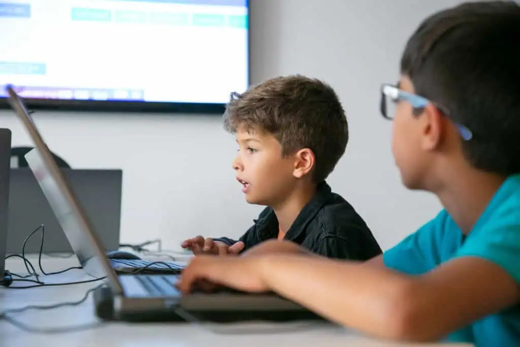 Due bambini, immersi nei loro computer portatili in un ambiente scolastico.