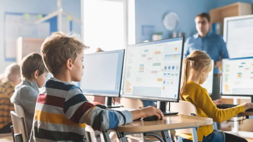 I bambini in classe usano i computer per esplorare linguaggi di programmazione.