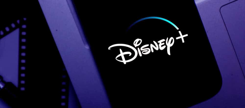 Il logo Disney+ illumina vividamente lo schermo, incorniciato da una nostalgica pellicola cinematografica che scorre sullo sfondo.