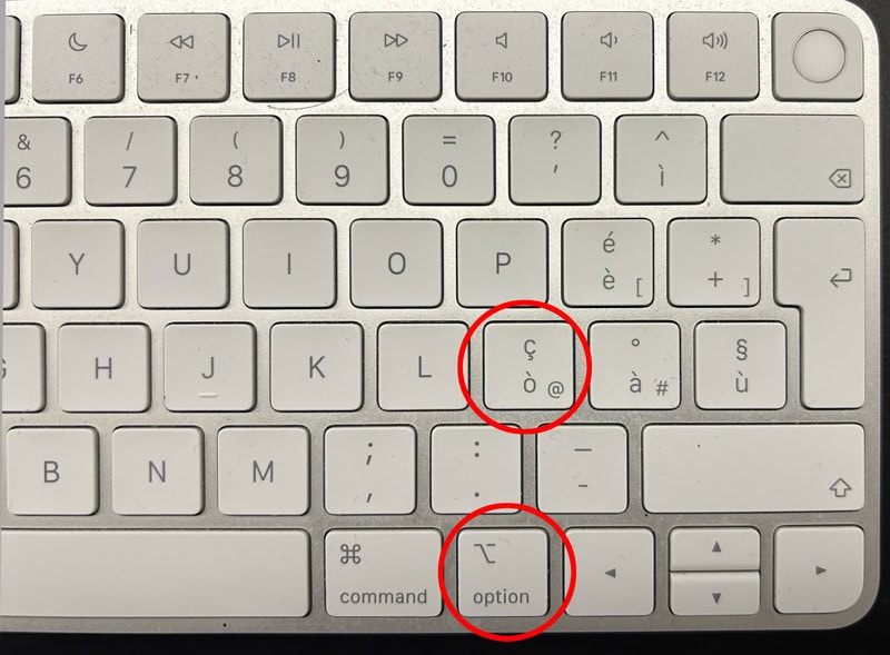Una tastiera Mac con due tasti cerchiati in rosso, che evidenziano i caratteri speciali e mostrano come fare la chiocciola su Mac.