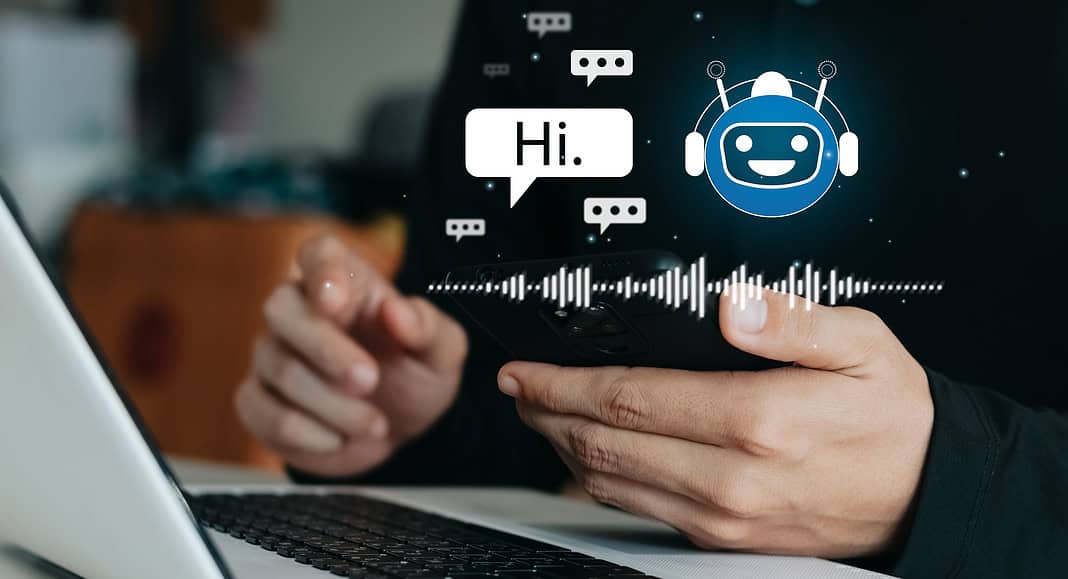 Una persona interagisce con uno smartphone e un laptop, connessi senza soluzione di continuità tramite l'icona del chatbot digitale e le forme d'onda vocali. ChatGPT facilita la loro comunicazione, aggiungendo un livello intelligente alla loro interazione virtuale.